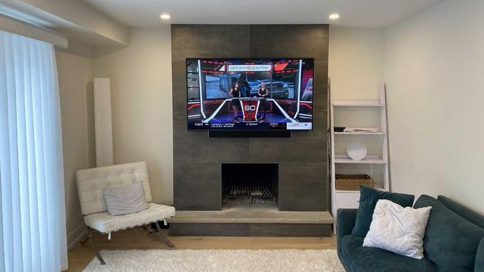 A living room with a fireplace and a flat screen tv on the wall.