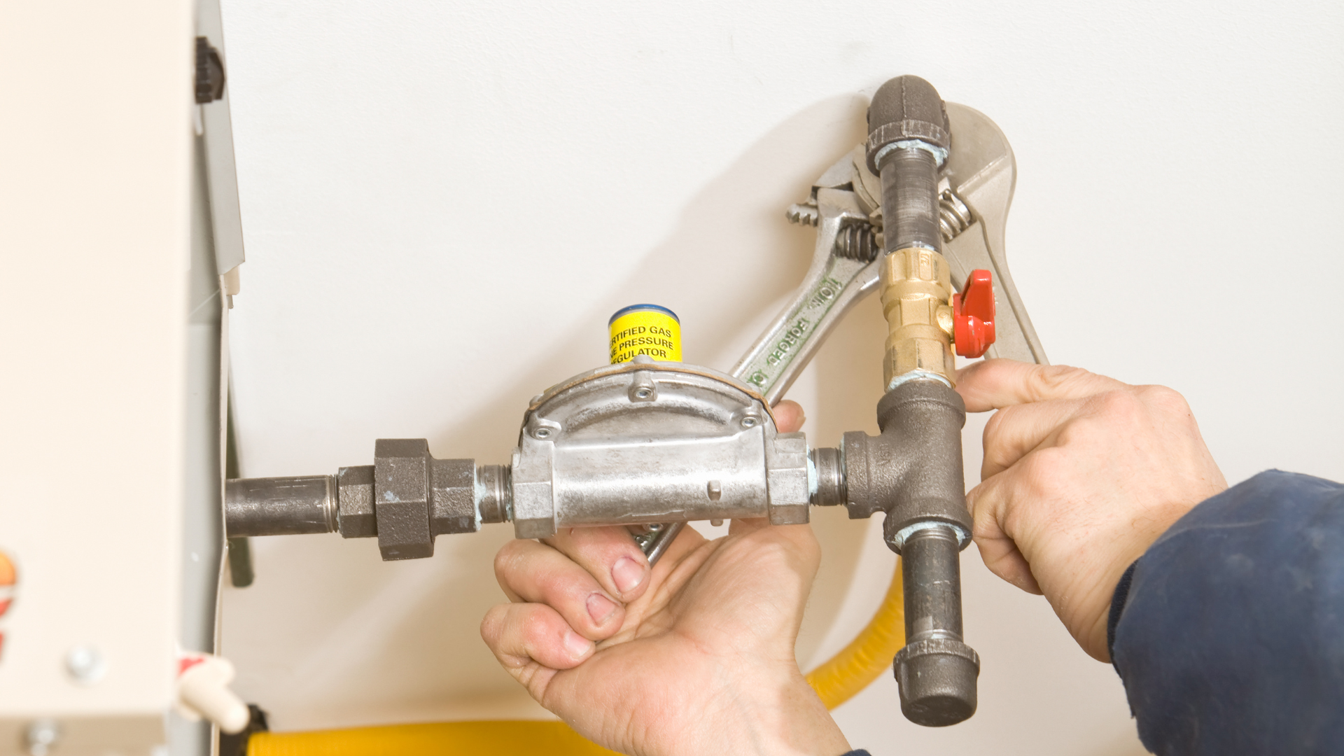 A person is fixing a pipe with a wrench.