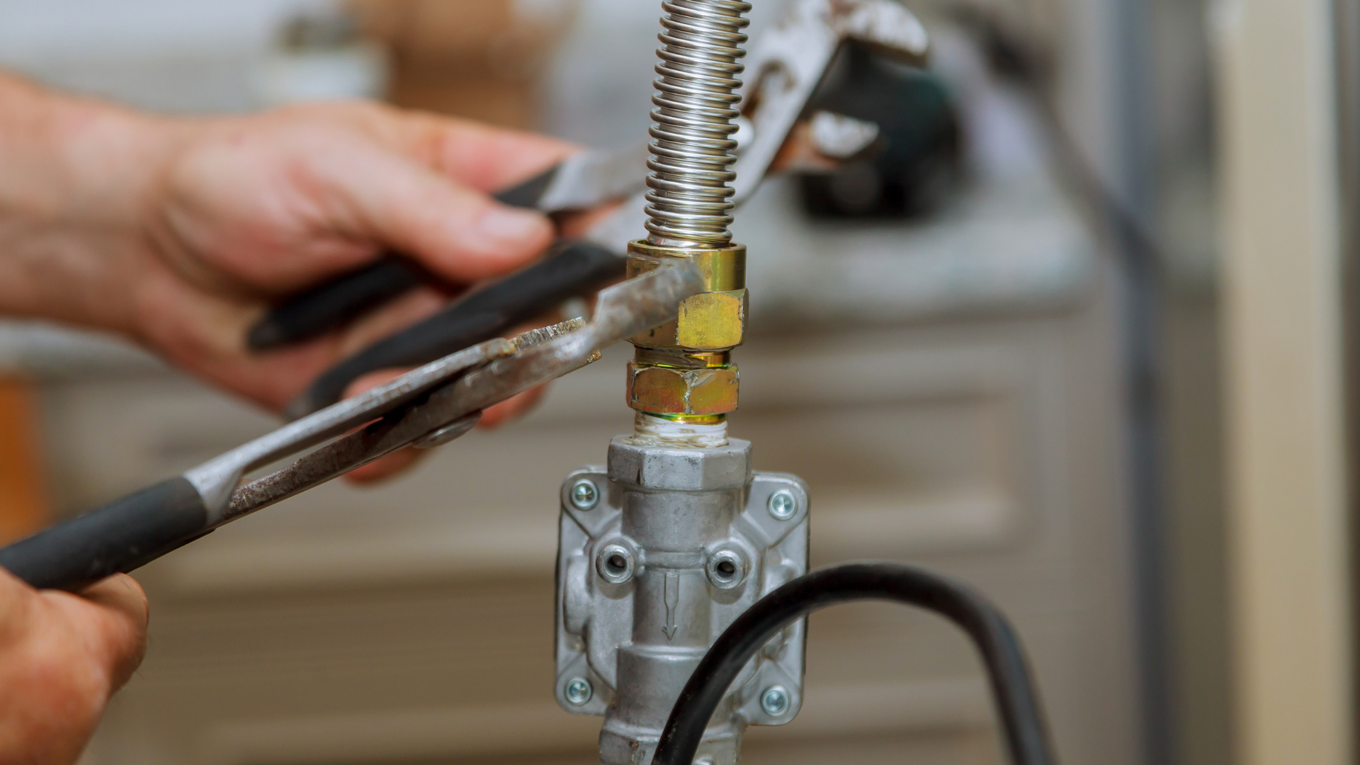 A person is fixing a faucet with a wrench and pliers.
