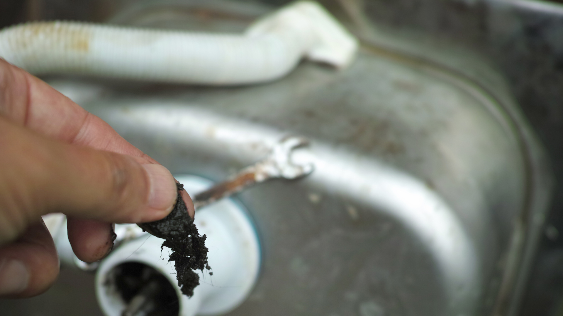 A person is holding a plunger over a sink drain.