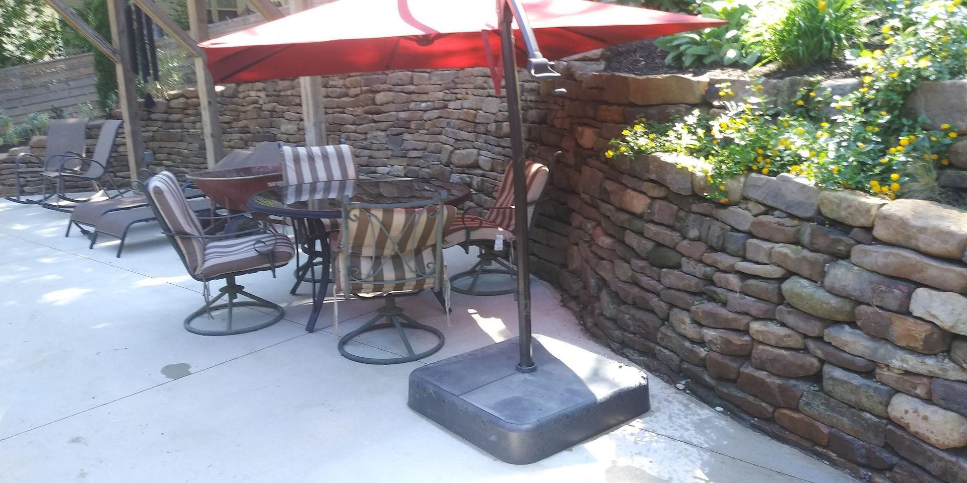 Patio with umbrella, chairs, and stone wall.