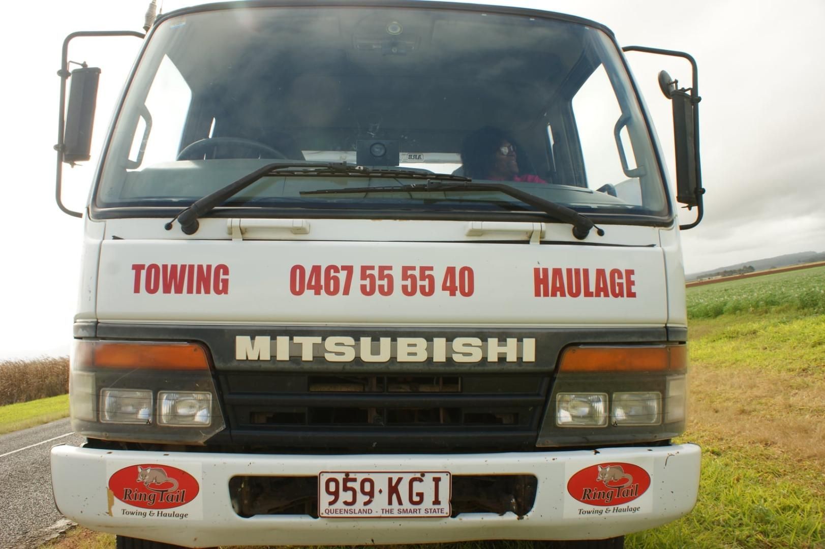 A Mitsubishi Towing Truck is Parked in a Grassy Field — Ringtail Towing in Atherton Tablelands, QLD