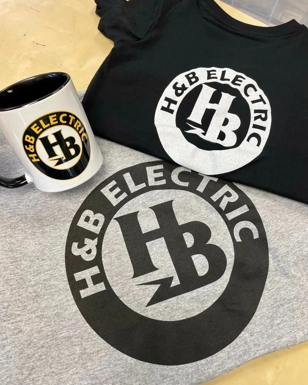 Two shirts and a mug with the h & b electric logo on them