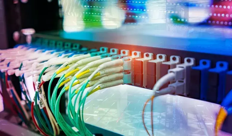 Server rack with colorful cables and connectors, illustrating data transfer and networking.