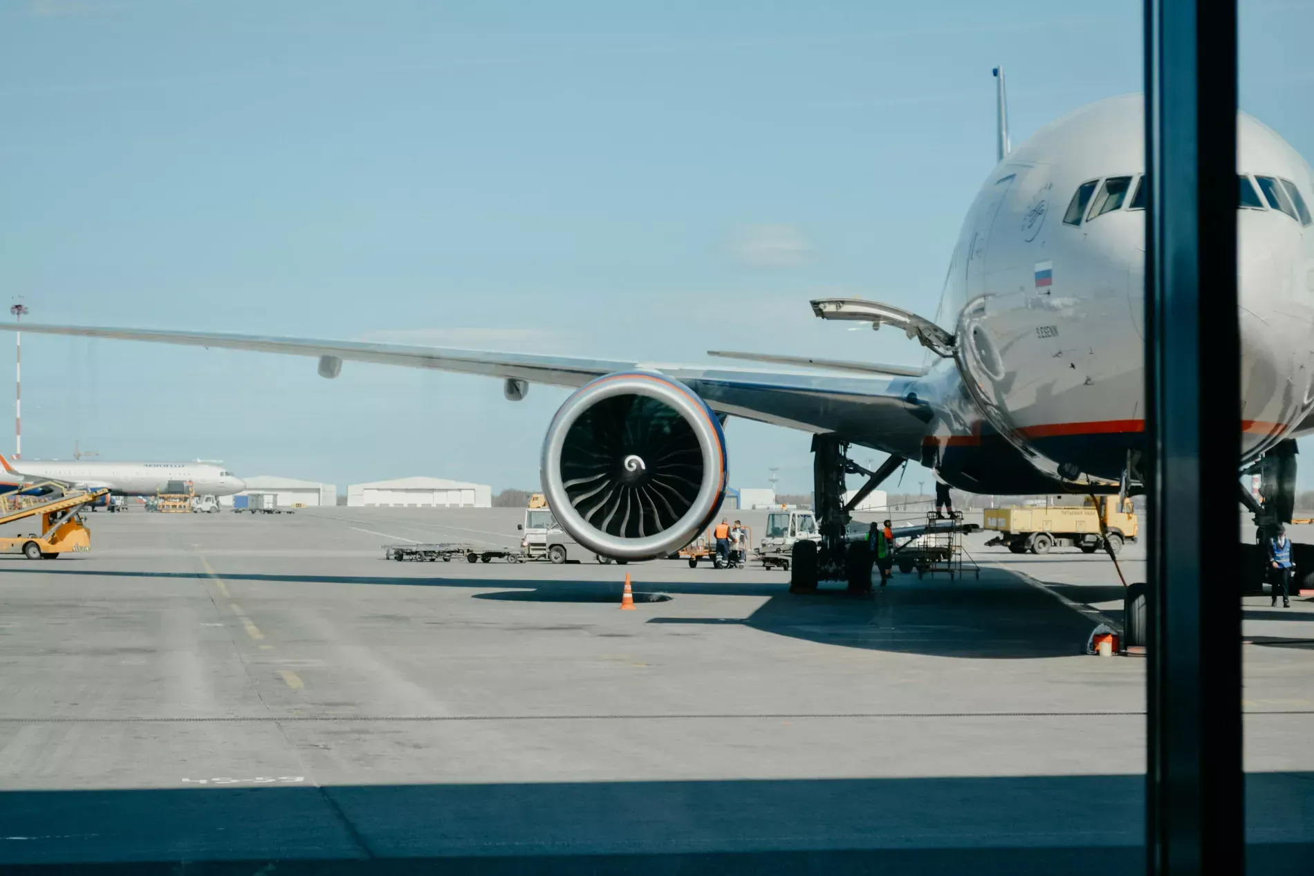 Airplane on the tarmac with a large engine and wings, sunny day.