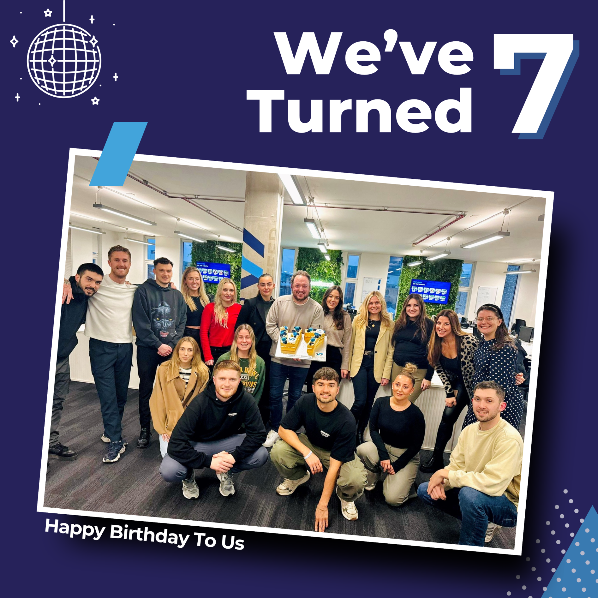 Group of people celebrating a 7th birthday, holding a cake in an office. Blue and white graphic elements.
