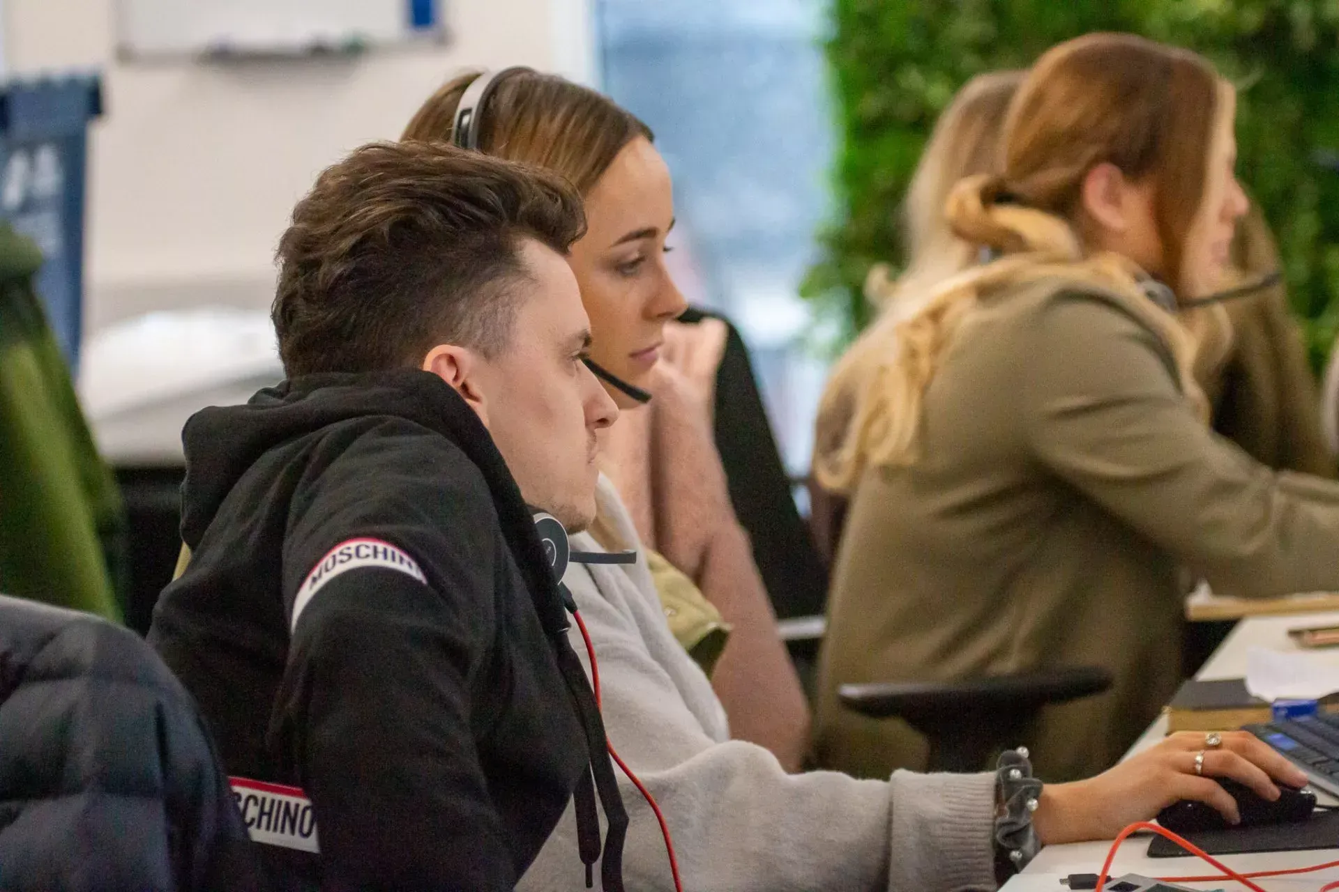 People at computers wearing headsets in an office.