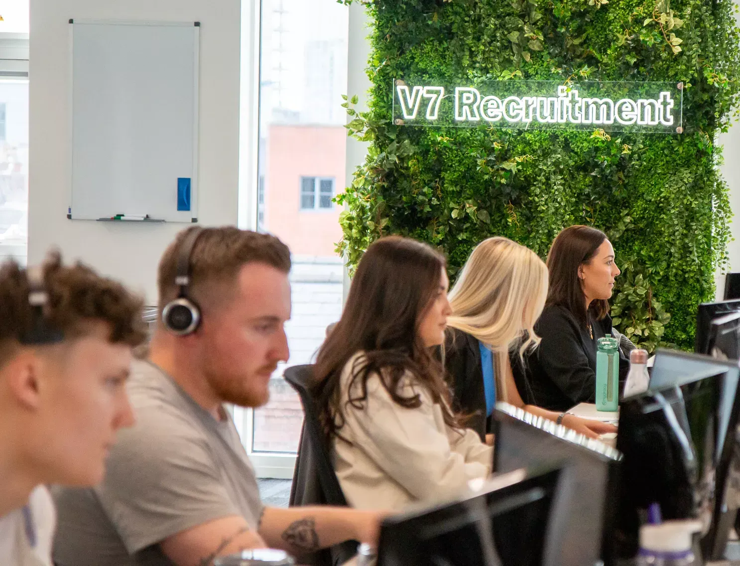 People working in an office, with a green wall and 