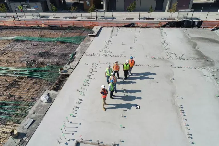 Construction workers on a concrete slab inspecting construction site.