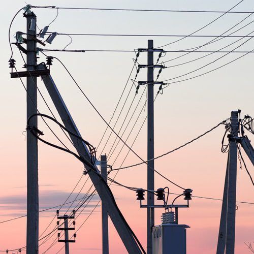 Power lines and utility poles against a pink and orange sky.