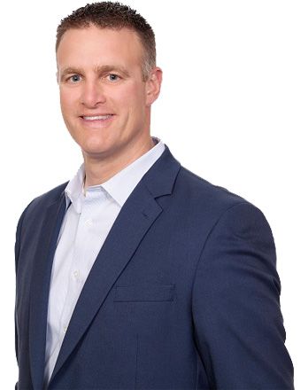 A man in a blue suit and white shirt is smiling for the camera.