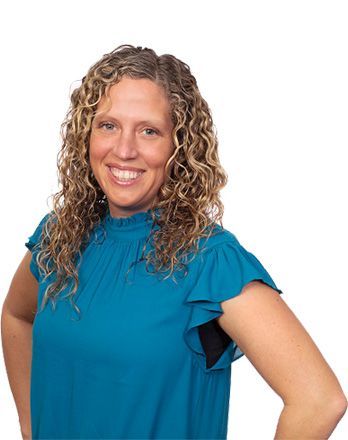 A woman with curly hair is wearing a blue shirt and smiling.