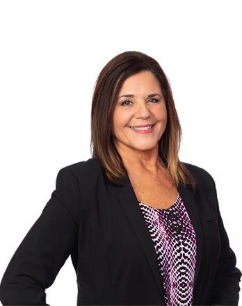 A woman wearing a black jacket and a purple shirt is standing in front of a white background.