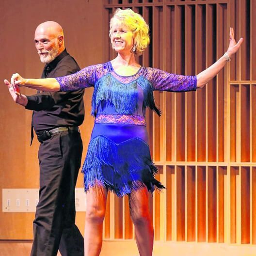 A man and a woman are dancing on a stage