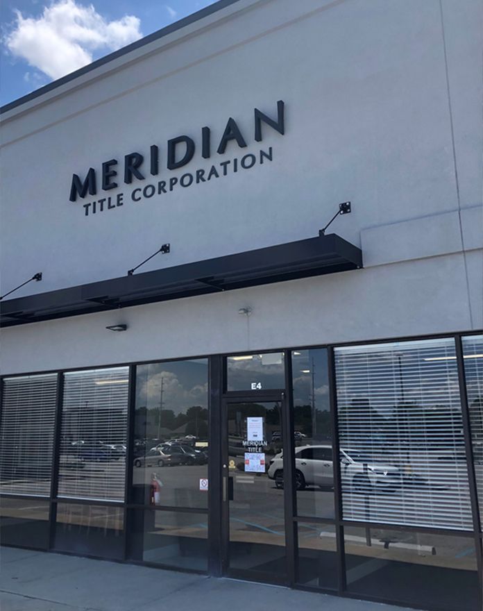 A white building with a black sign that says meridian title corporation