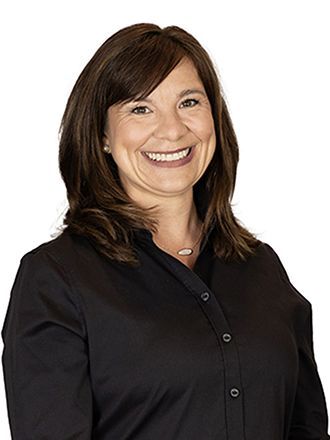 A woman in a black shirt is smiling for the camera.