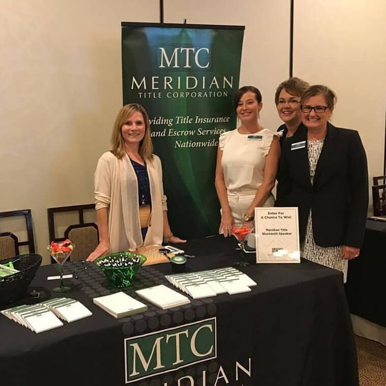 A group of women standing around a table for mtc meridian title corporation