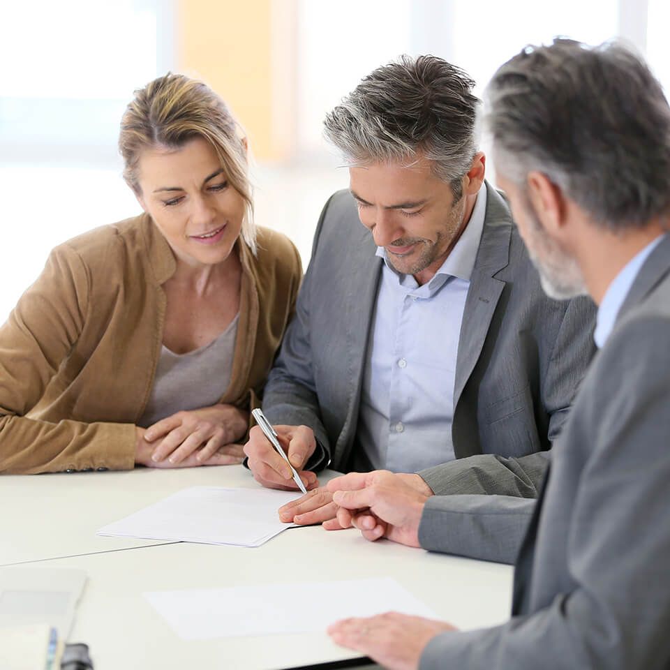 A group of people are sitting at a table signing a document.