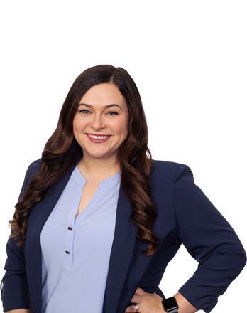 A woman wearing a blue jacket and a blue shirt is standing with her hands on her hips.