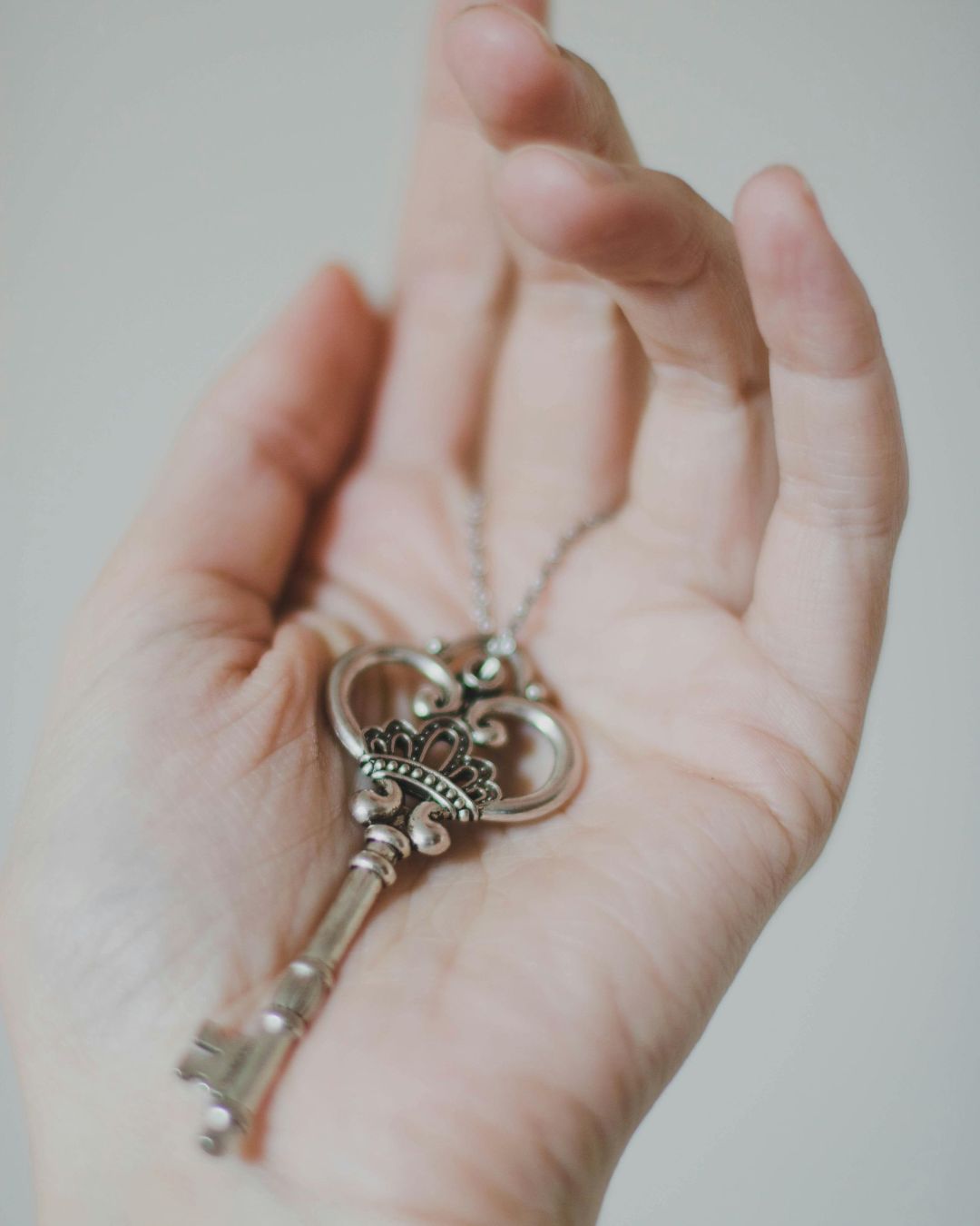 A person is holding a key with a crown on it in their hand.