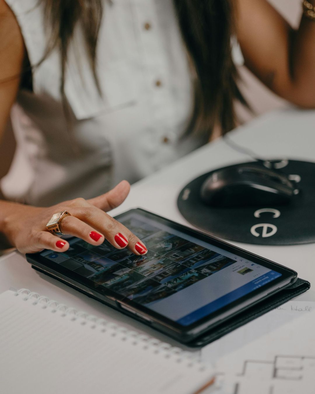 A woman with red nails is using a tablet