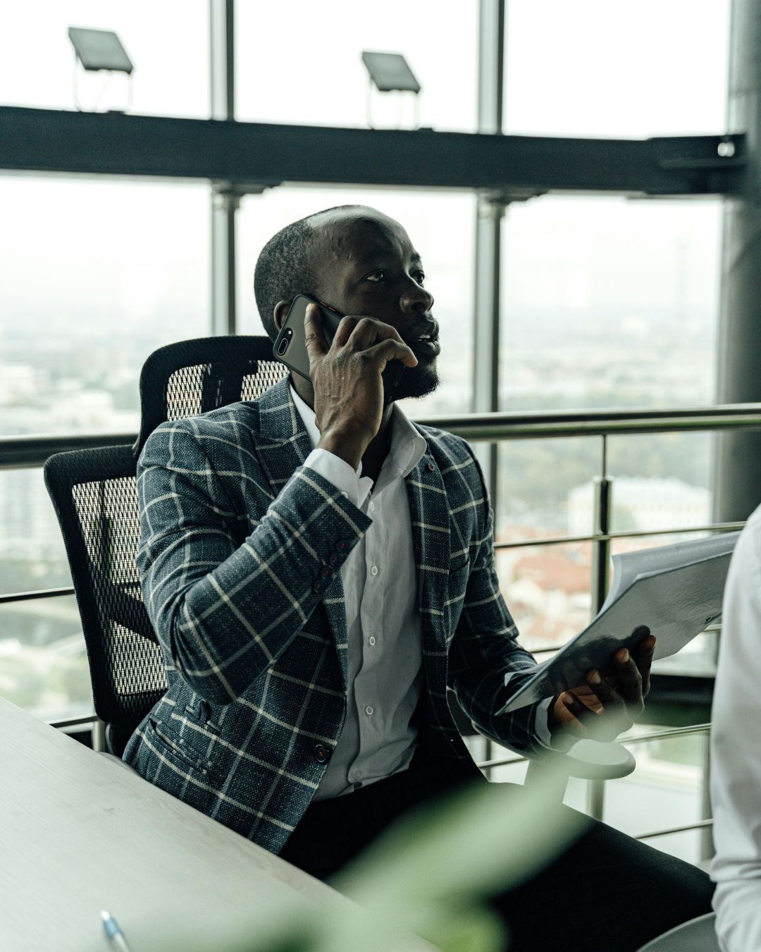 A man is sitting at a table talking on a cell phone.