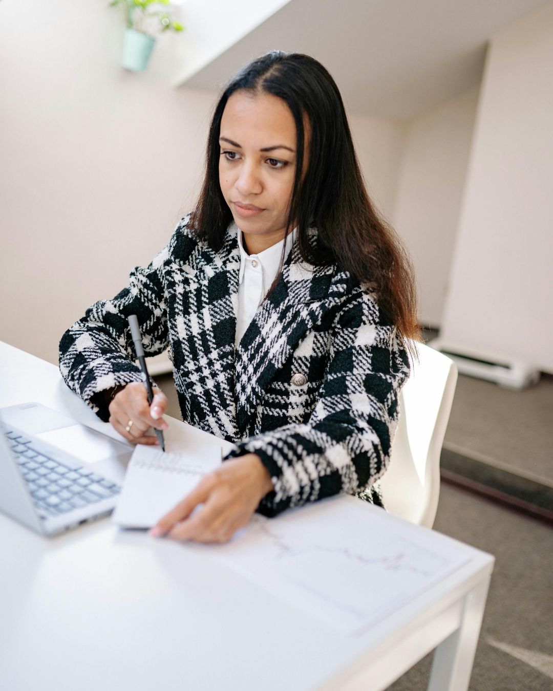 A woman is sitting at a desk using a laptop computer.