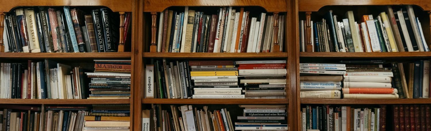 A library filled with lots of books on wooden shelves.