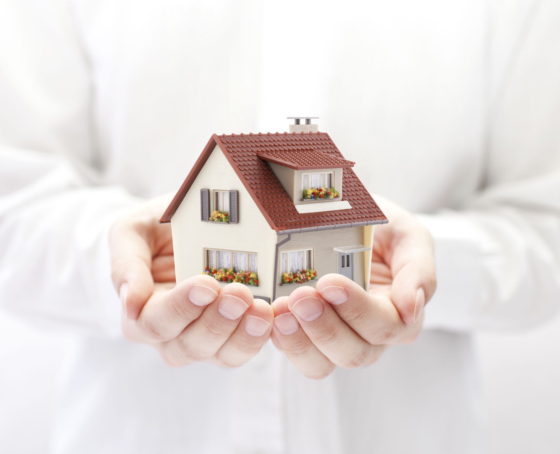 A person is holding a small model house in their hands.