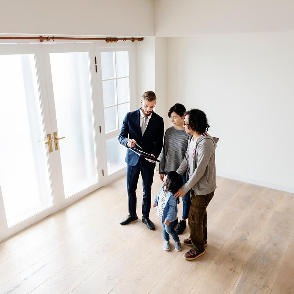 A group of people are standing in an empty room looking at a house.