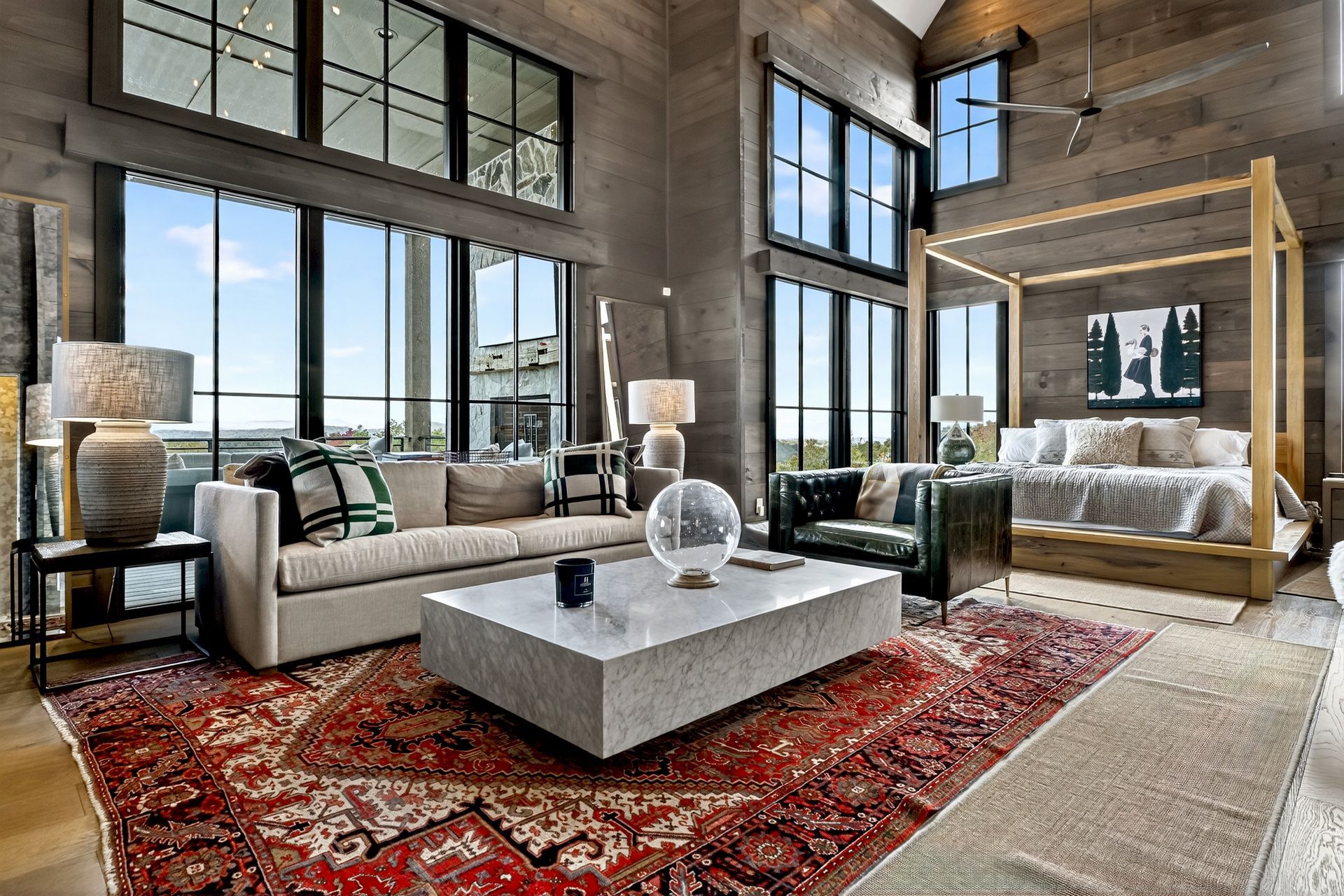 Spacious bedroom with a four-poster bed, large windows, and a Persian rug.