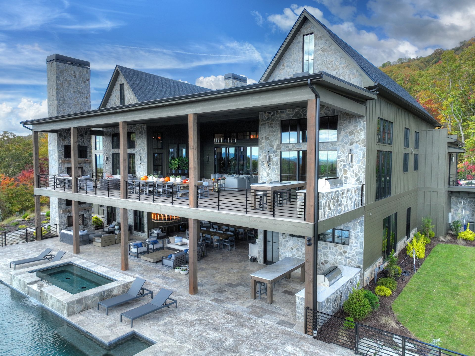 Luxurious multi-story home with a pool and covered decks, mountain backdrop.