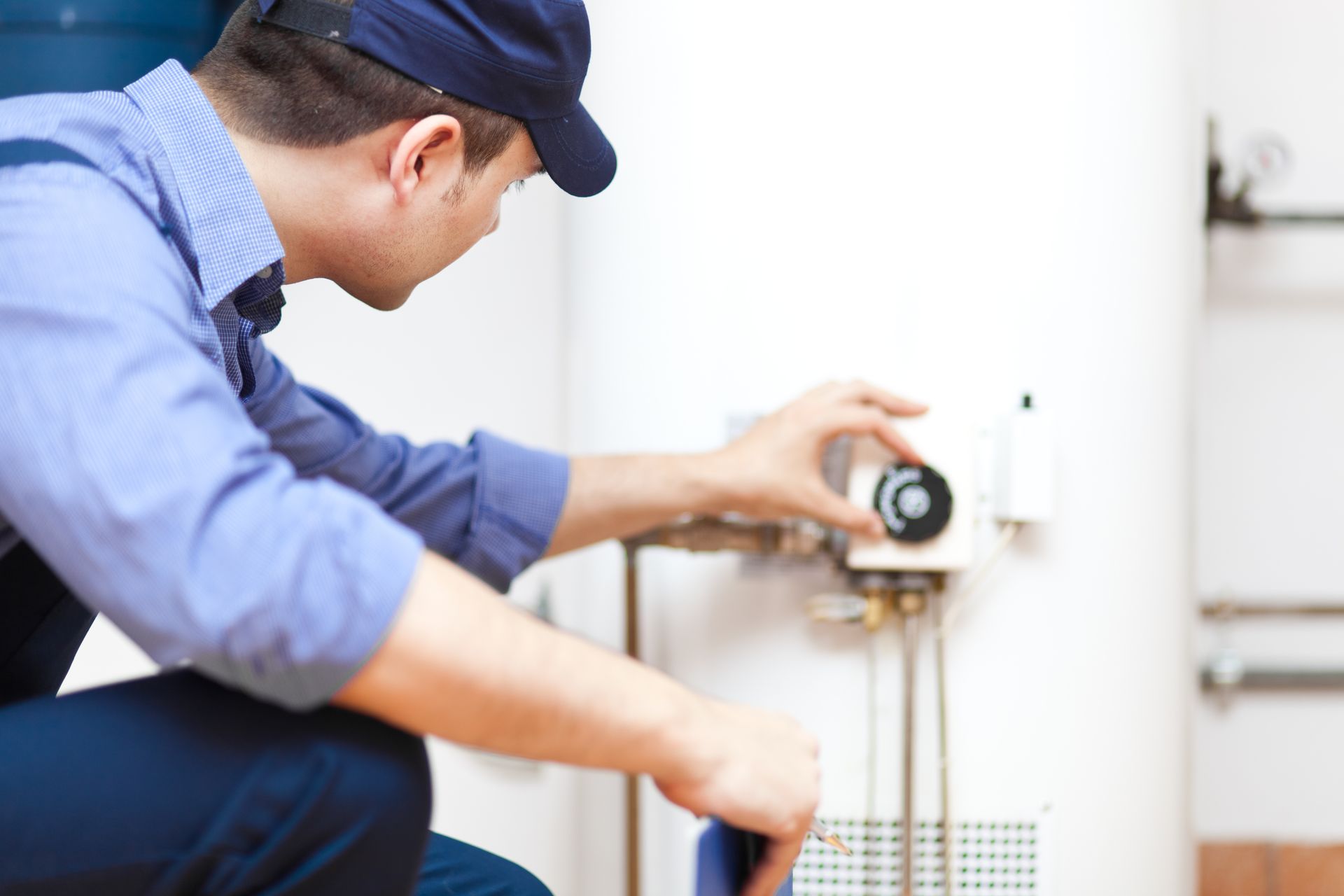 a man wearing a hat is working on a water heater
