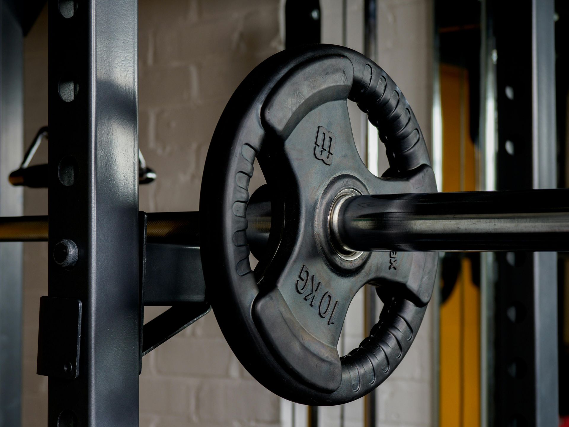 Black weight plate on a barbell in a gym rack, close-up view