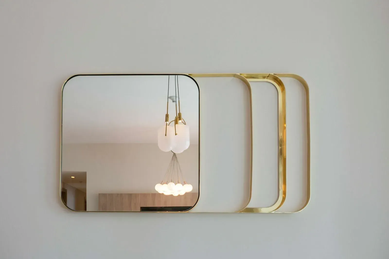A mirror with a gold frame is hanging on a white wall.