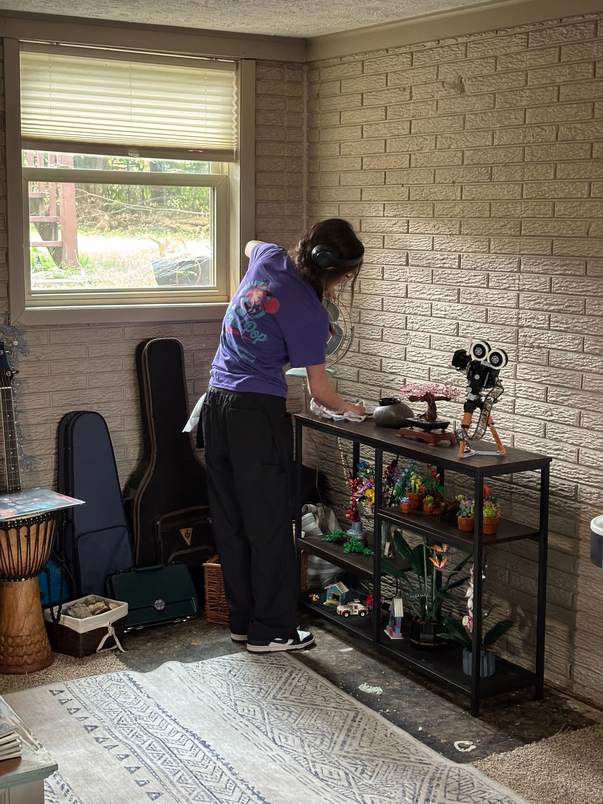 Person tidies items on a black shelf in a room with a brick wall and window Person tidies items on a black shelf in a room with a brick wall and window