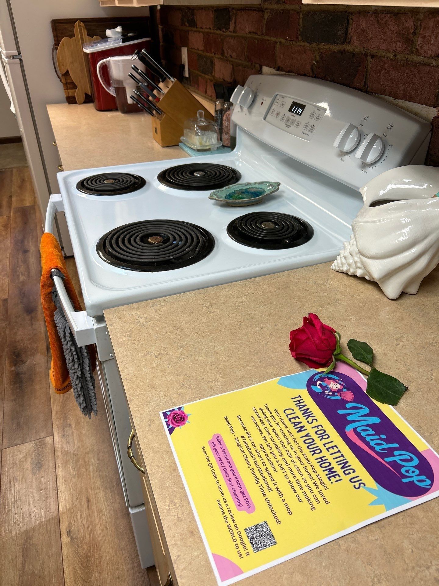 Kitchen counter with an electric stove, cleaning supplies, and a Maid Pop flyer