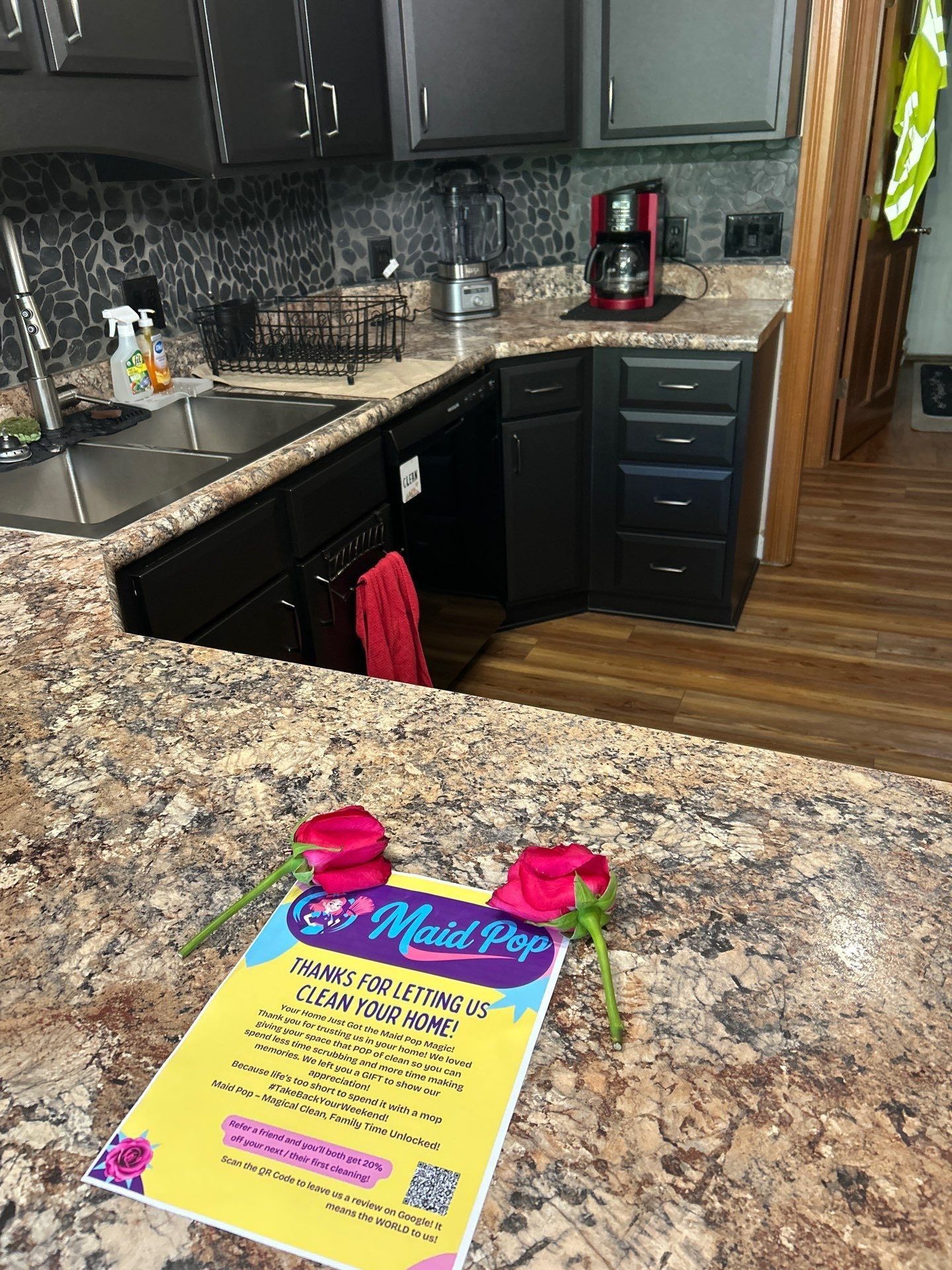 Kitchen with countertop, Maid Pop flyer, red roses, and black cabinets