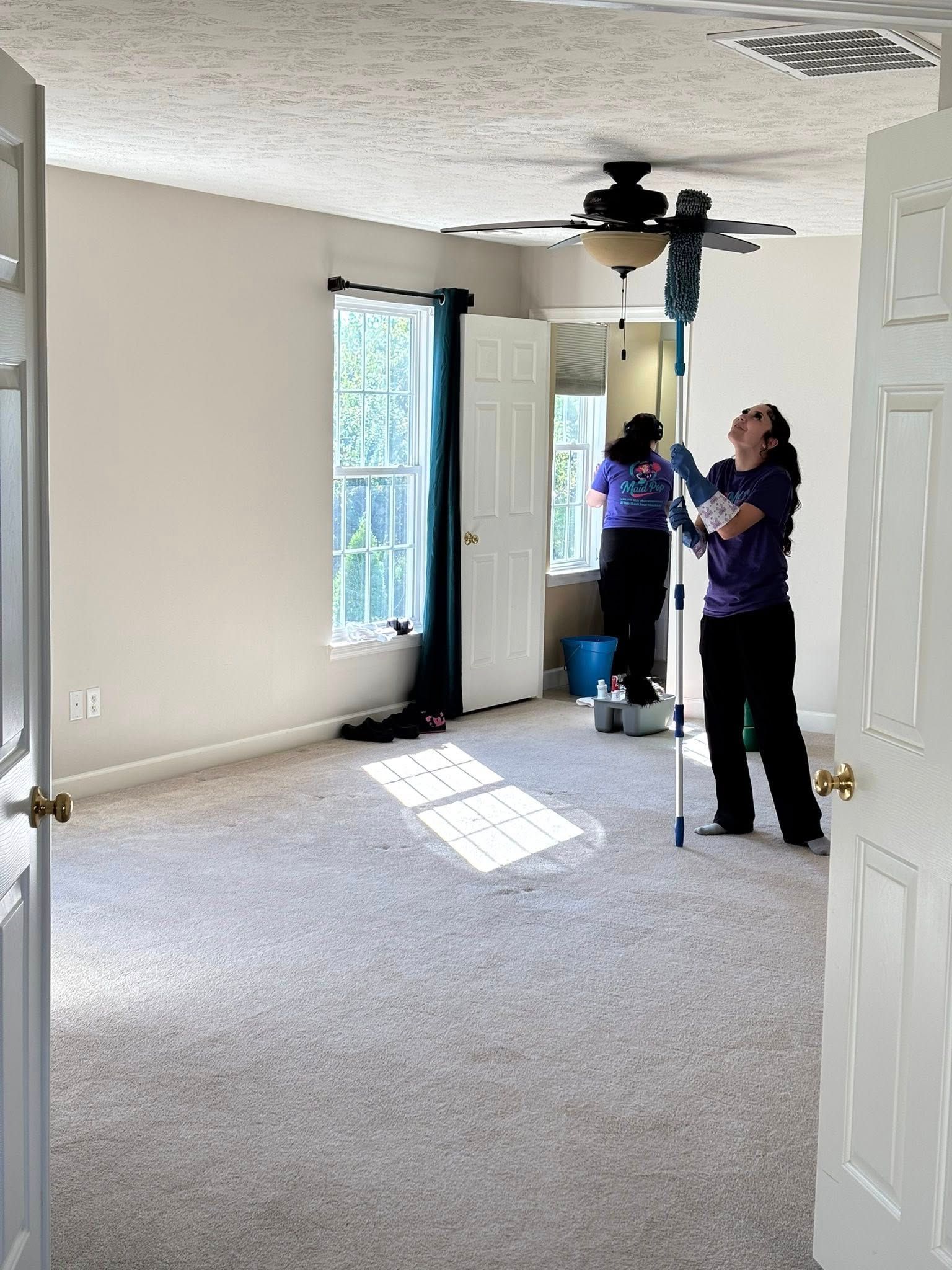Two people cleaning a bedroom