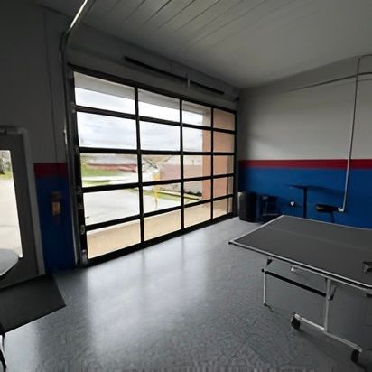 A spacious shop interior with a large glass garage door, a table, and blue and red accents on the walls