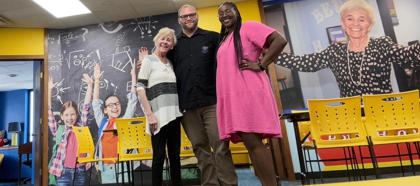 Three people pose in a colorful room