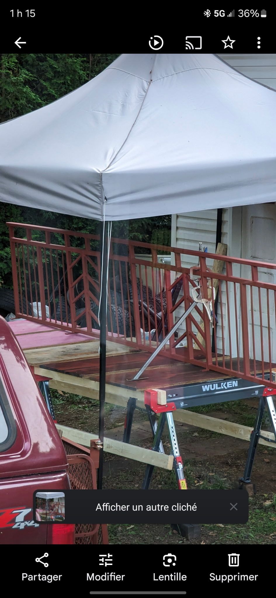 Un camion rouge est garé sous un auvent blanc pendant que quelqu'un travaille sur une rampe.