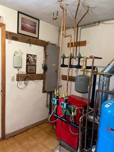 A room with a red boiler and copper pipes.