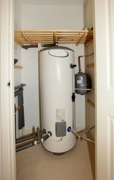 A large white water heater is sitting in a closet