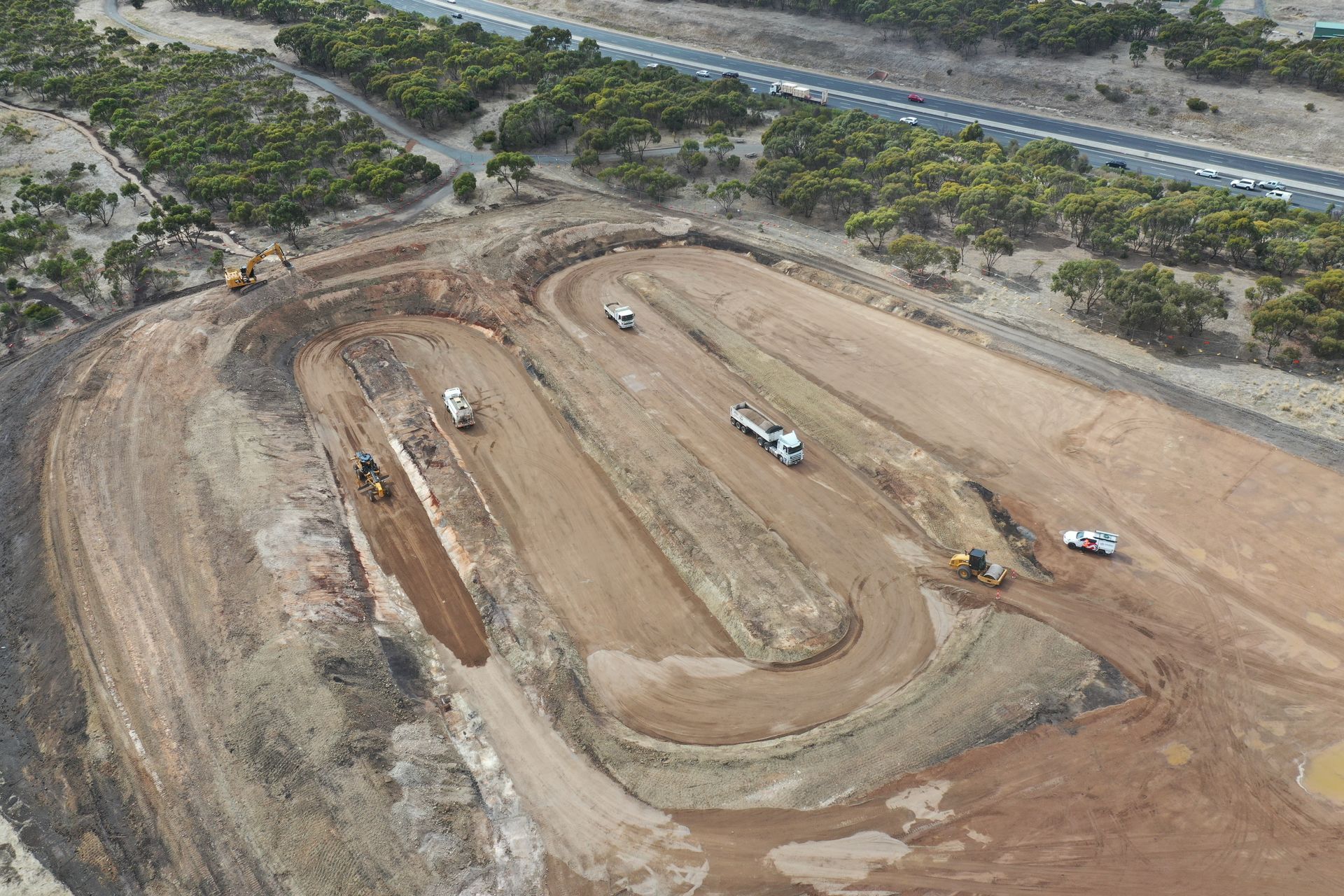 An aerial view of a construction site with a highway in the background.