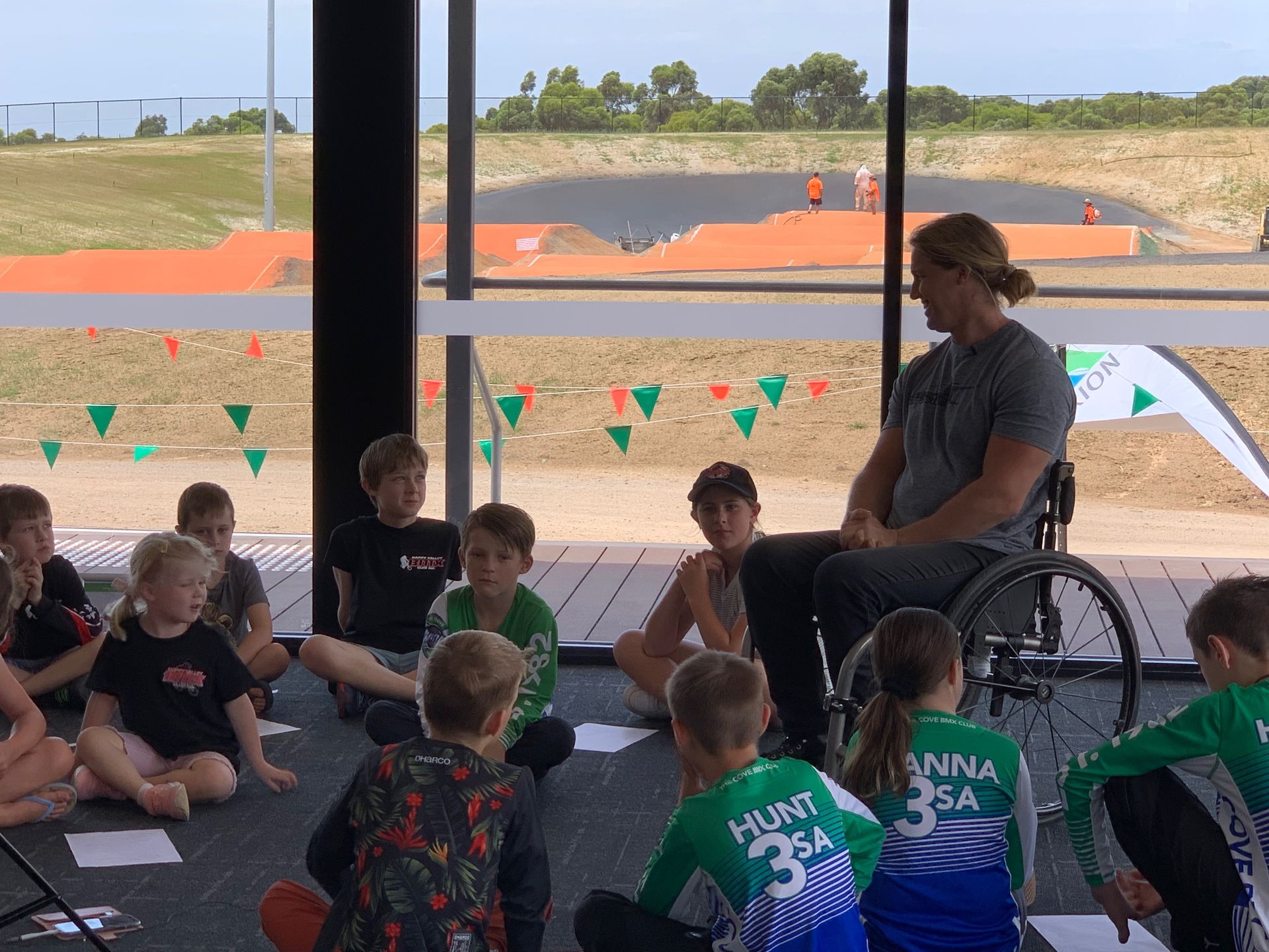 A man in a wheelchair is talking to a group of children
