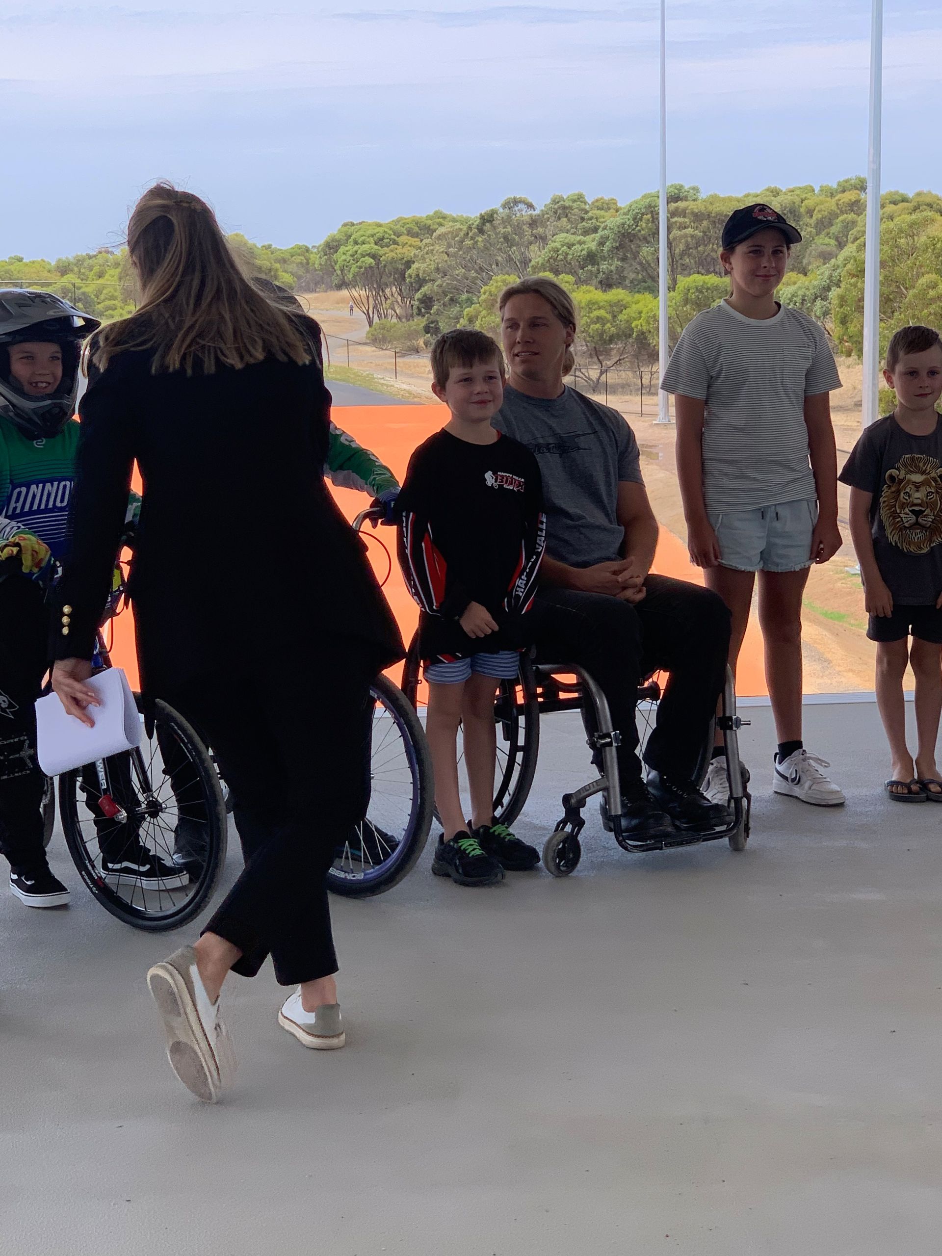 A group of people are standing around a man in a wheelchair