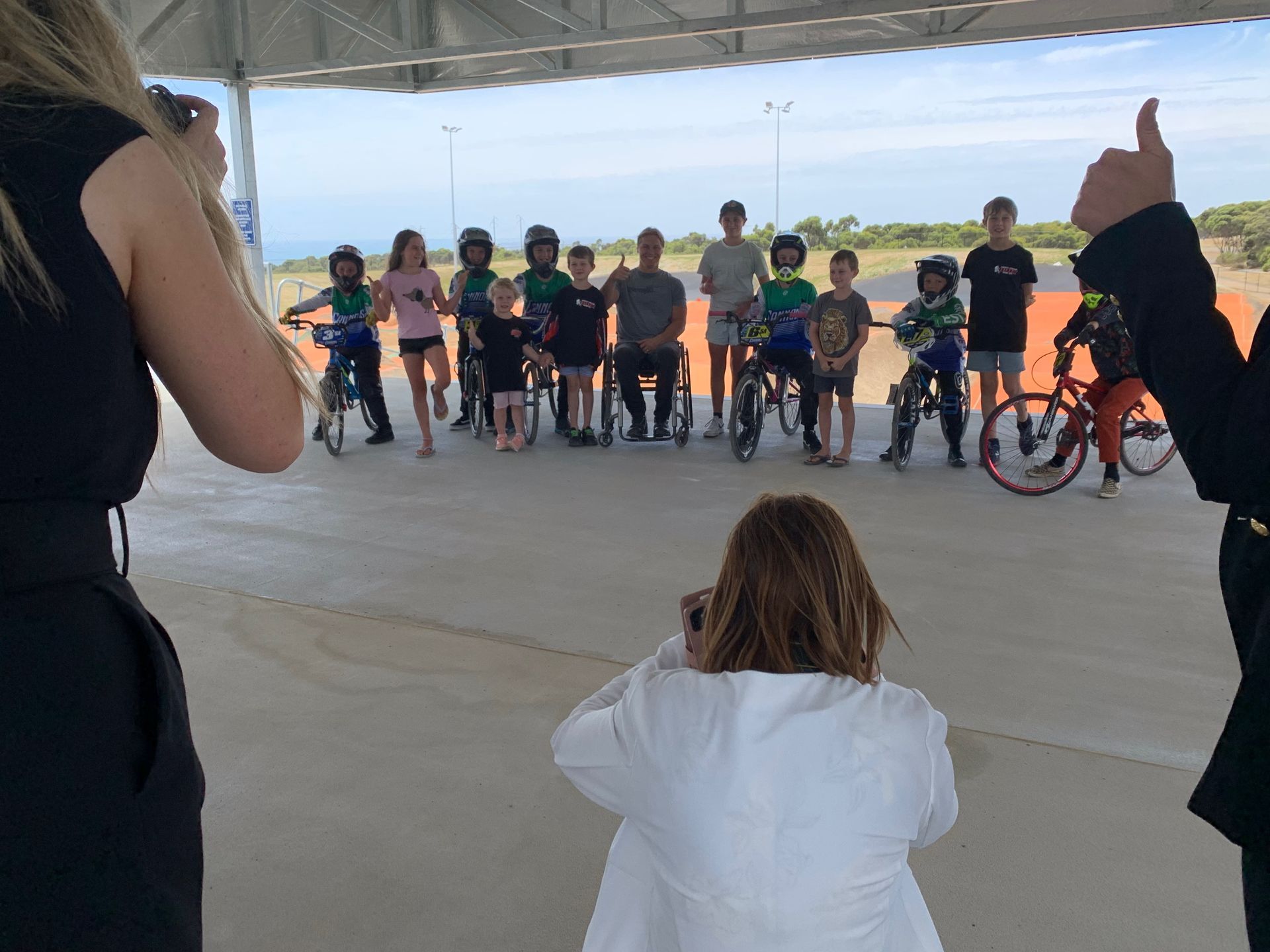 A woman is taking a picture of a group of children on bikes.