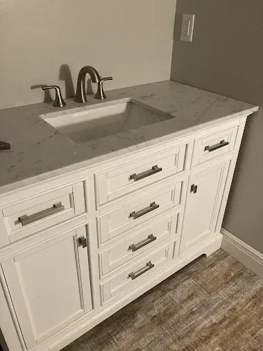 White bathroom vanity with a marble countertop, sink, and brushed nickel fixtures.