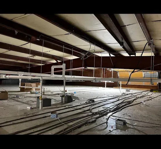 Industrial interior with exposed beams, wiring, and metal infrastructure.